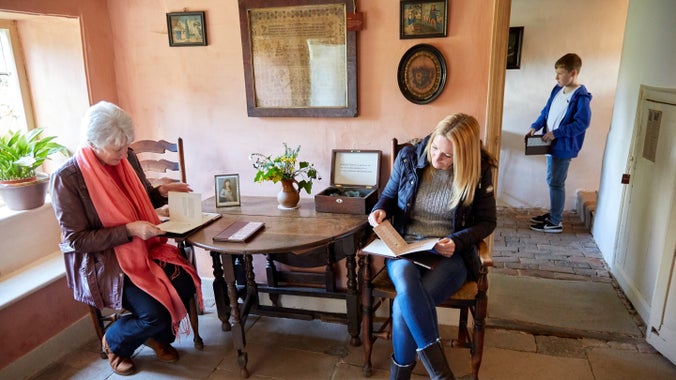 Visitors reading documents and exploring inside Hardy's Cottage, Dorset